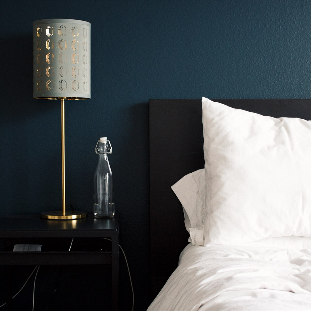 Brass bedside lamp with a patterned drum shade on a dark bedside table