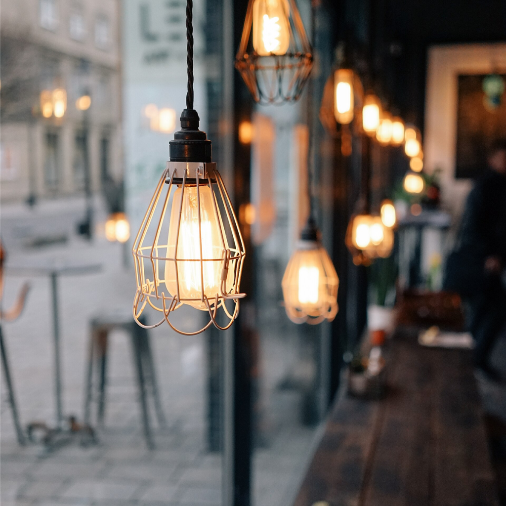 Caged bulb pendant lights glowing in a row above a dark counter