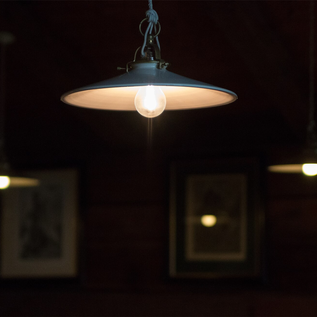 Dark metal dome pendant light glowing above a dining table