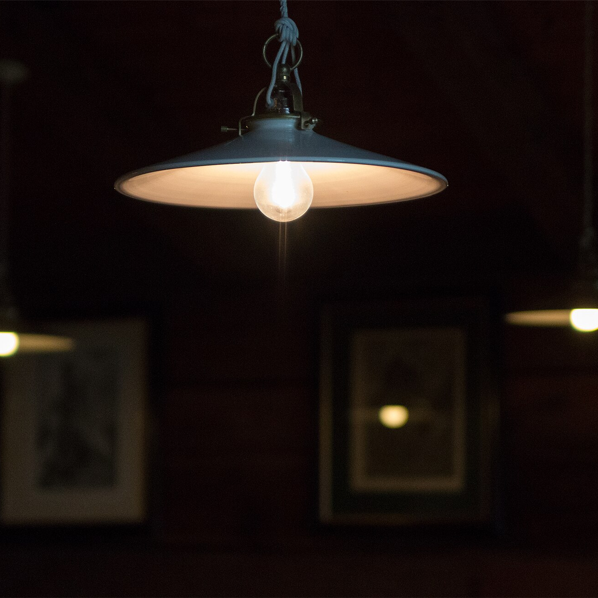 Dark metal dome pendant light glowing above a dining table