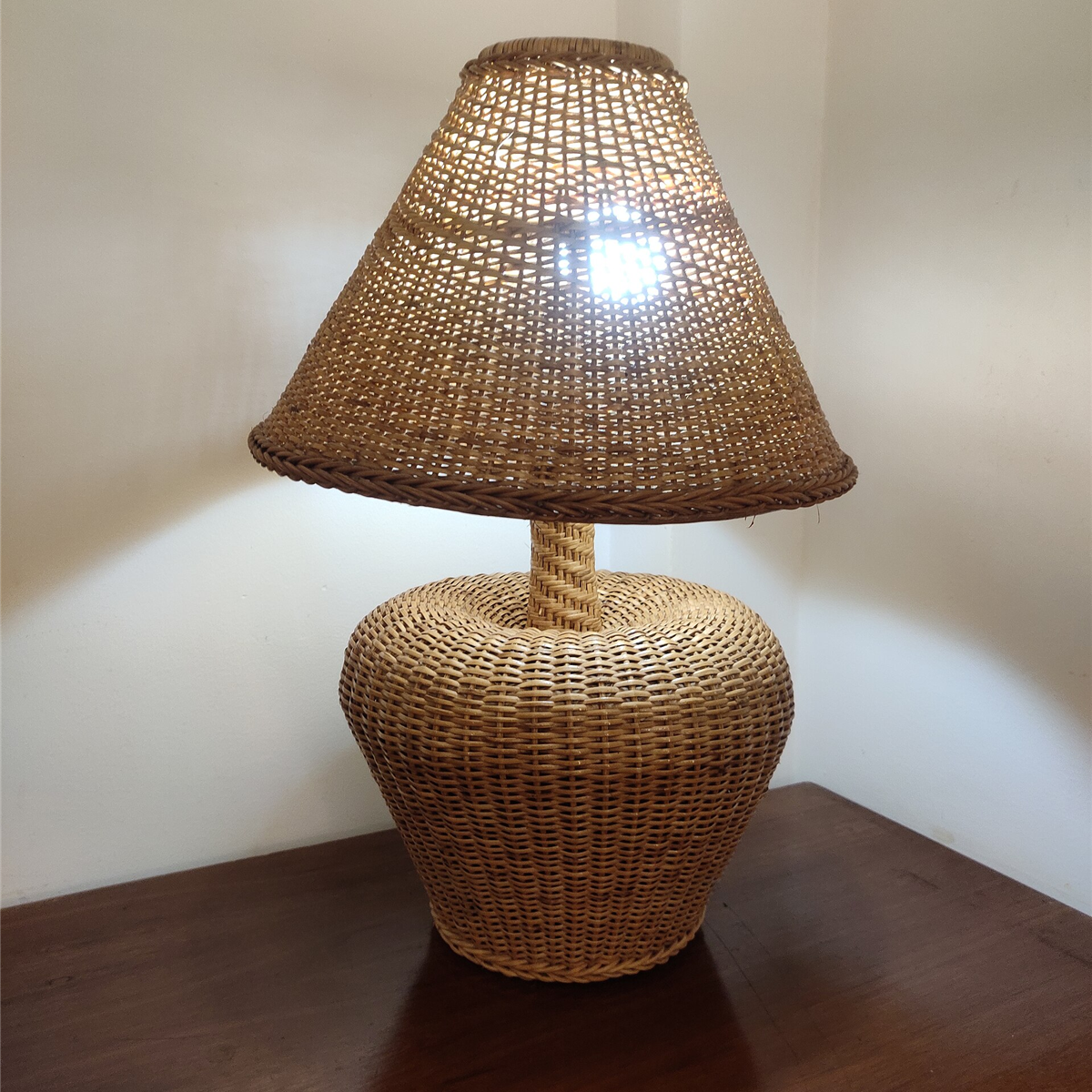 Woven rattan table lamp with a matching shade on a wooden console