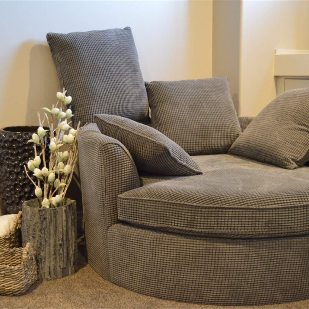 Round lounge armchair in oat fabric with scatter cushions and woven baskets